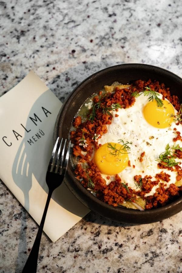 Huevos en cazuela de barro junto a la carta de Calma