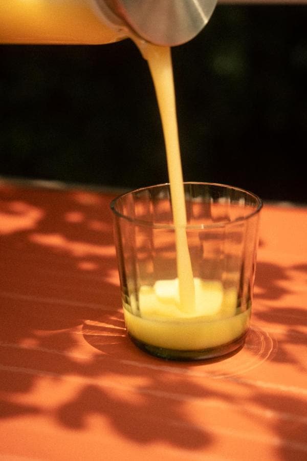 Jugo que se sirve en un vaso, sobre una mesa terracota al sol