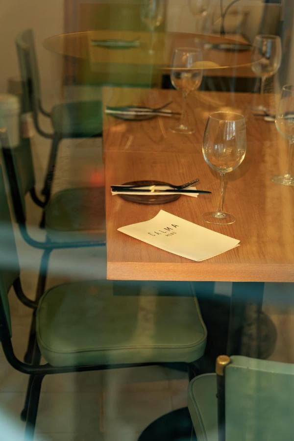 Una mesa puesta con copas y la carta, junto a sillas verdes