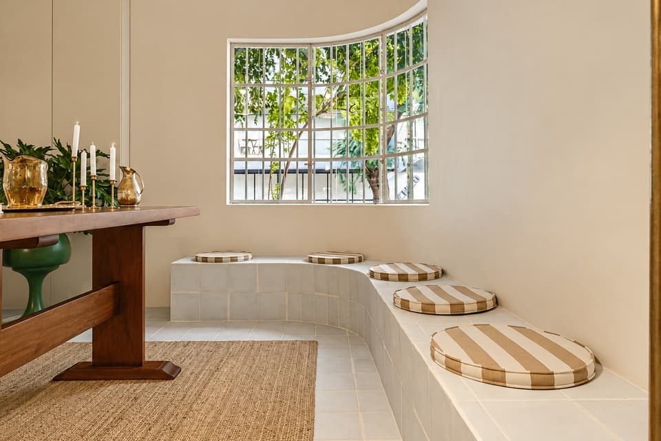 A built-in bench with striped cushions under the curved window