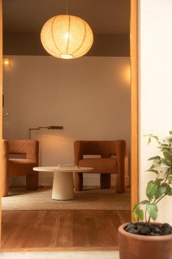 Dos sillones y una mesa redonda bajo una lámpara de papel