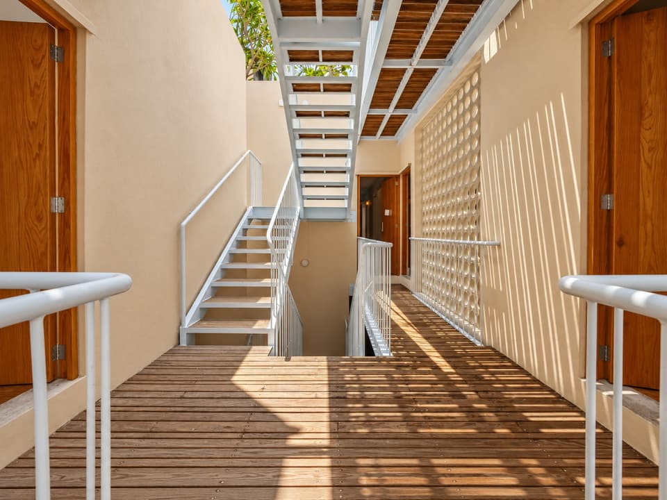 The steel stair and a timber walkway beside a screen, in the light well