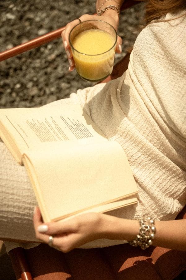 Una huésped con un libro abierto y un vaso de jugo